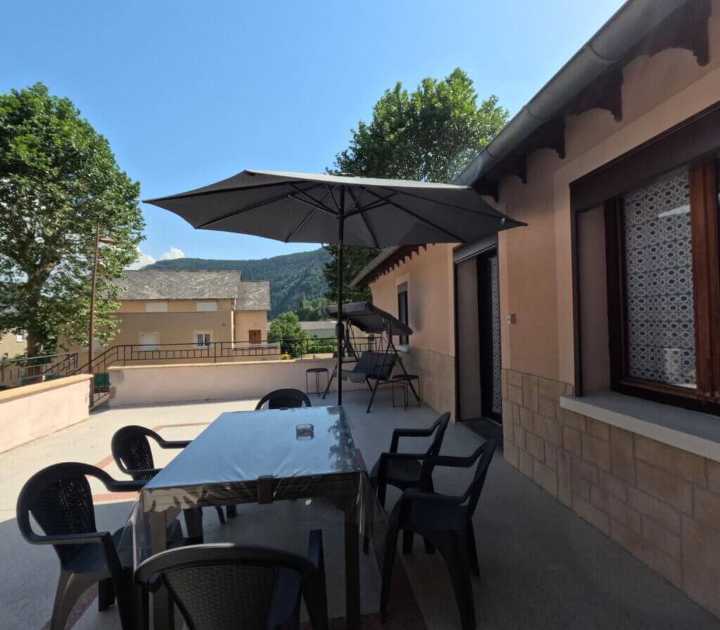 Terrasse ombragée l'aprés-midi au Pont de la Gineze avec vue sur les montagnes de la Margeride et des parapentes dans le ciel.